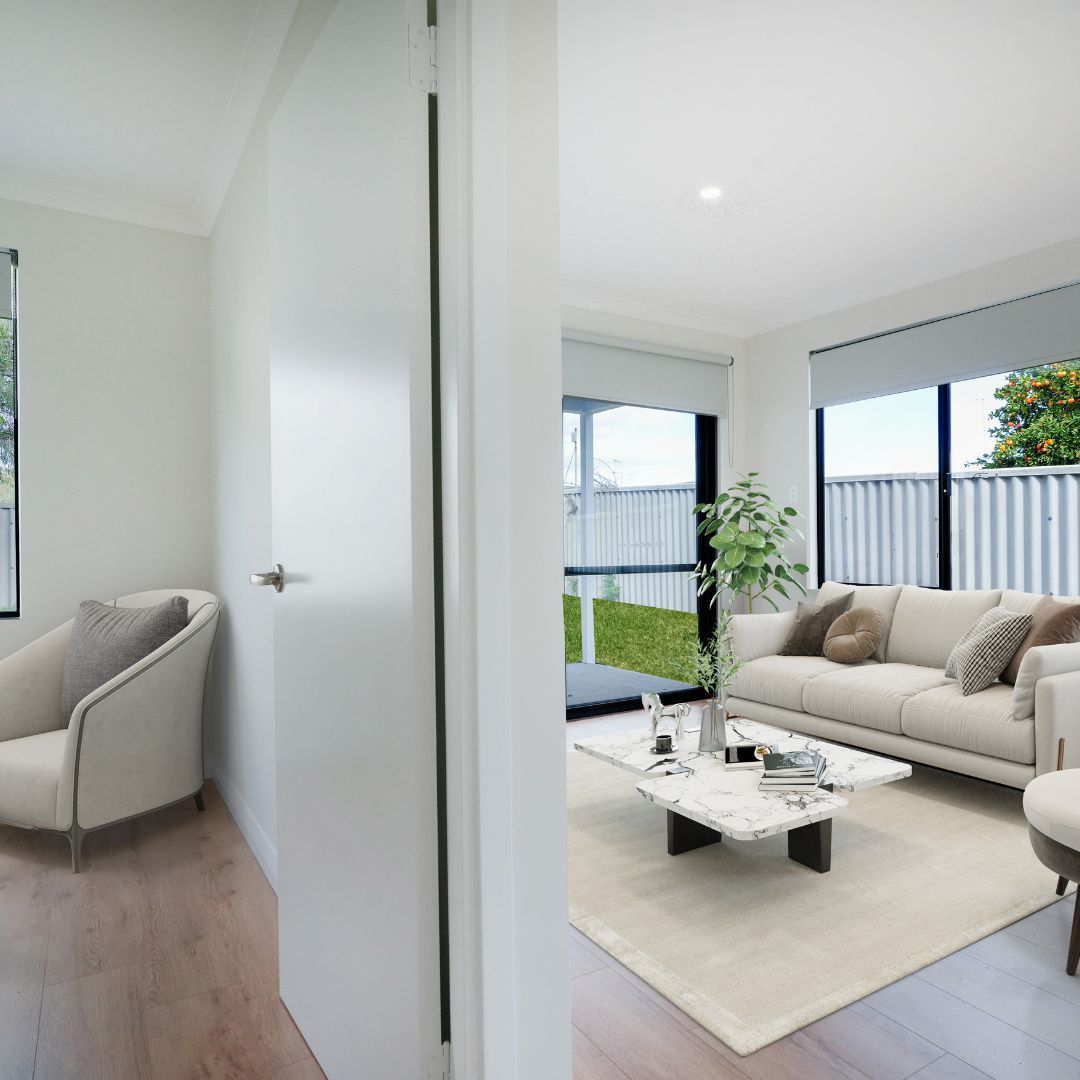 A bright living room viewed through a doorway, featuring a beige sofa, a white marble coffee table, and a plush armchair.