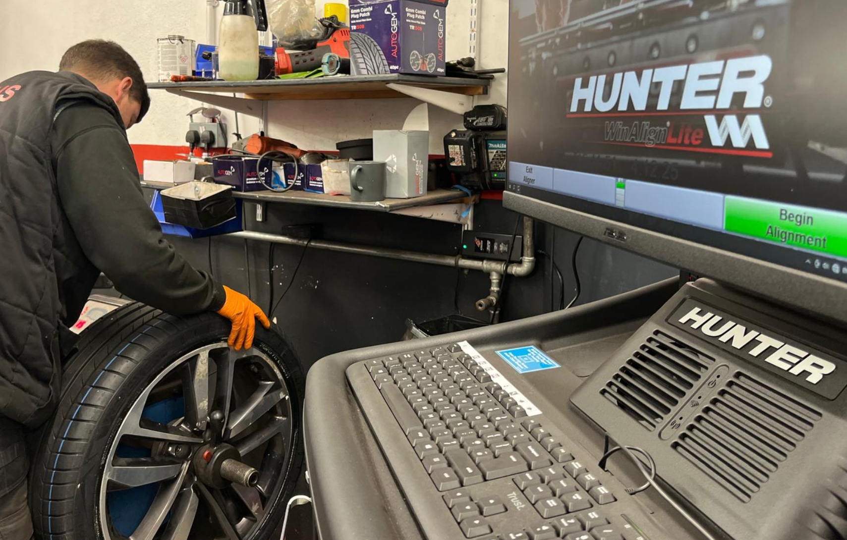 Mechanic balances a car tire on a Hunter wheel balancer in a shop.