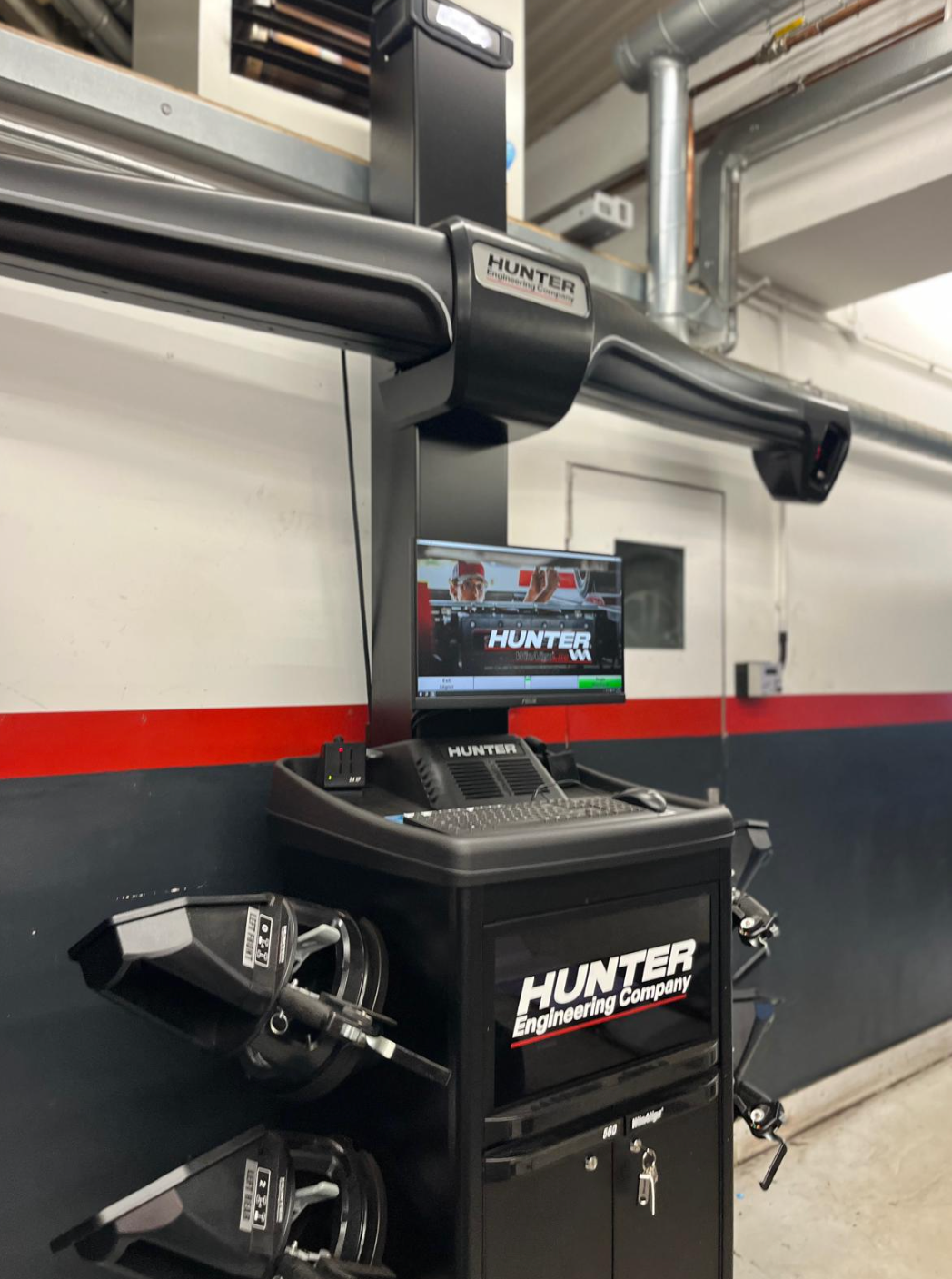 Hunter wheel alignment machine in a garage setting, with a computer screen and wheel alignment tools.
