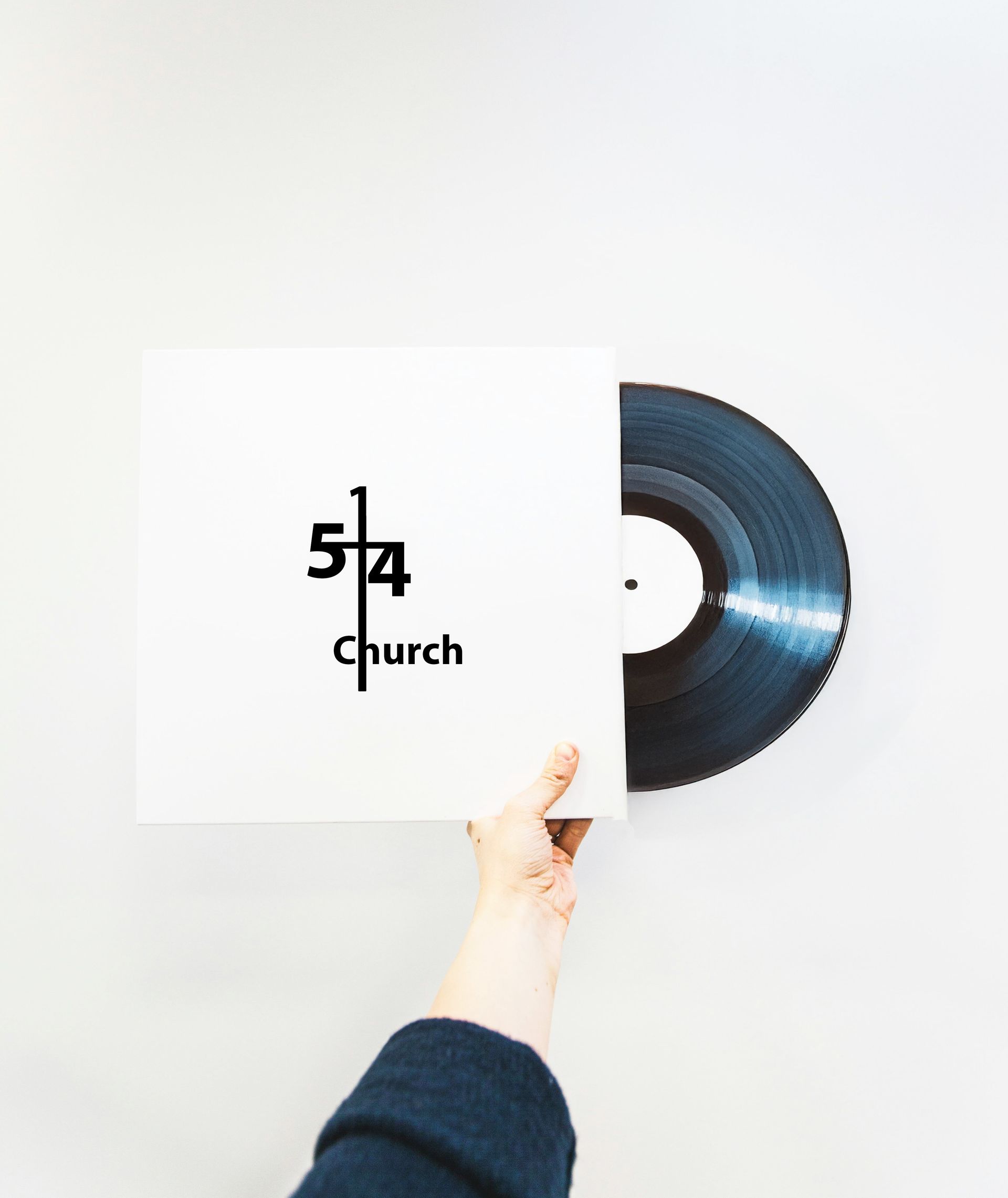 Hand holding a vinyl record partly in its white sleeve, the label reads 