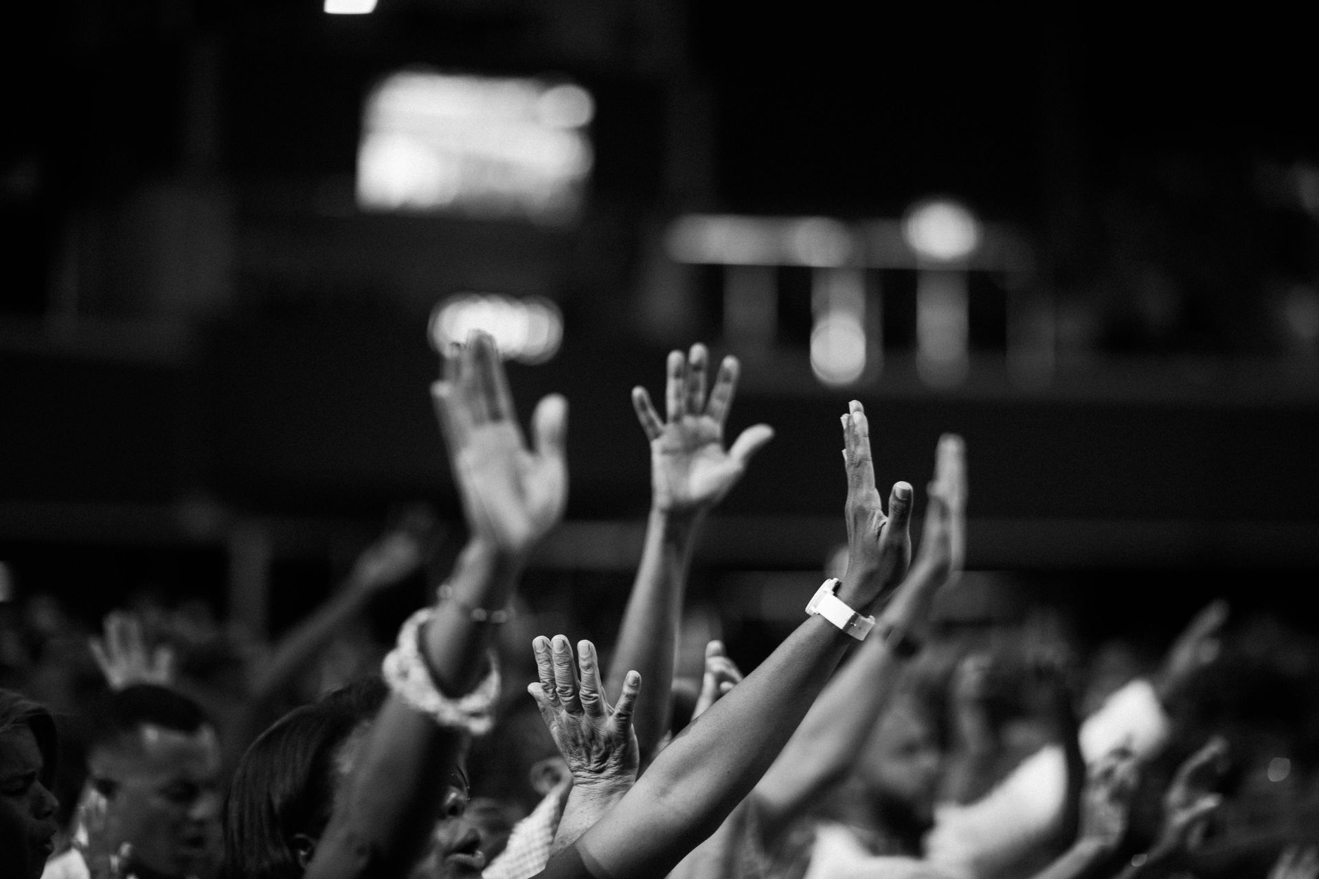 Crowd of people with arms raised in the air, possibly in worship or celebration. Black and white.