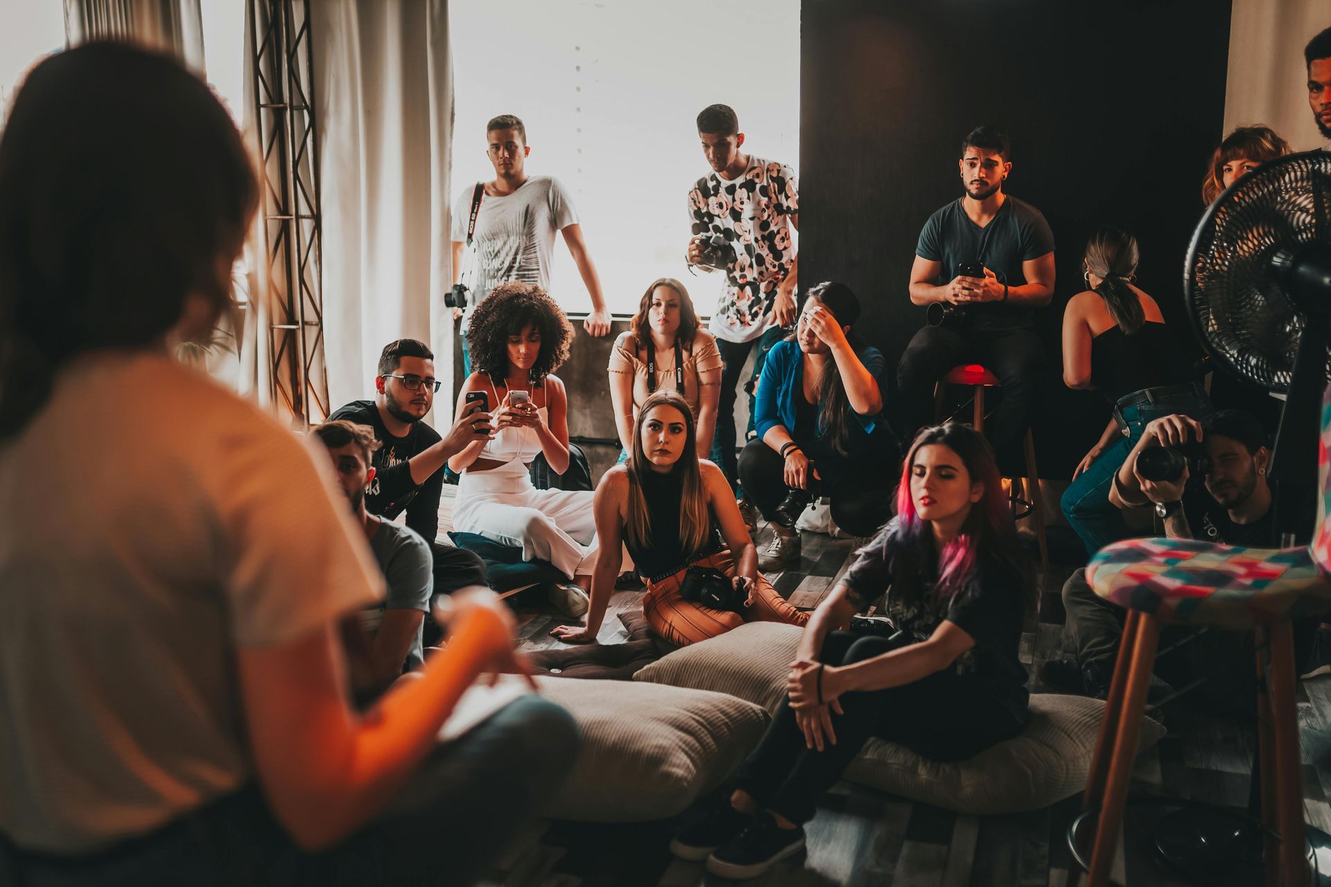 Group of diverse people listening to a speaker in a casual indoor setting.