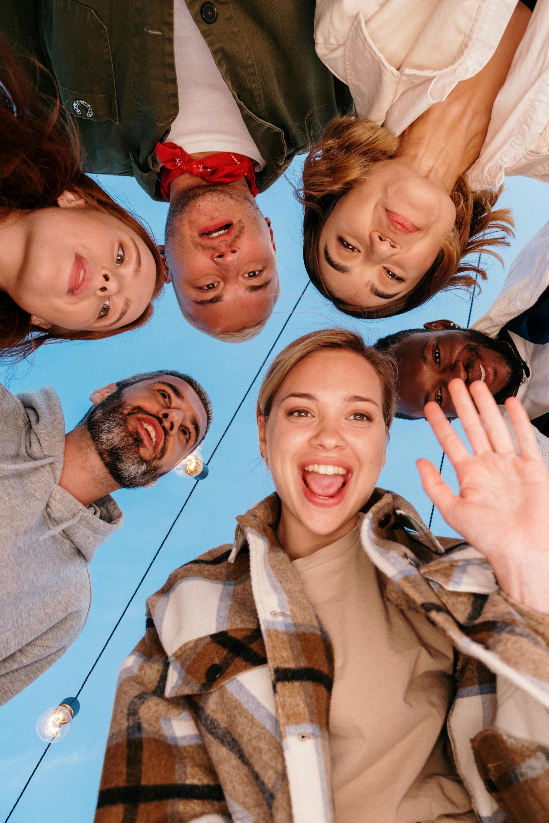 Group of six people looking down at the camera with smiles and open expressions.
