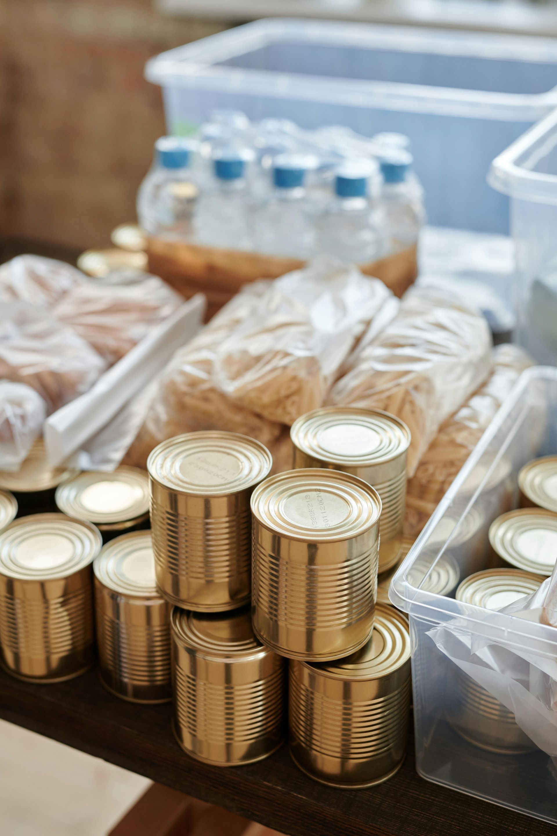 Cans, bottled water, and packaged food on a table, likely for a food drive.