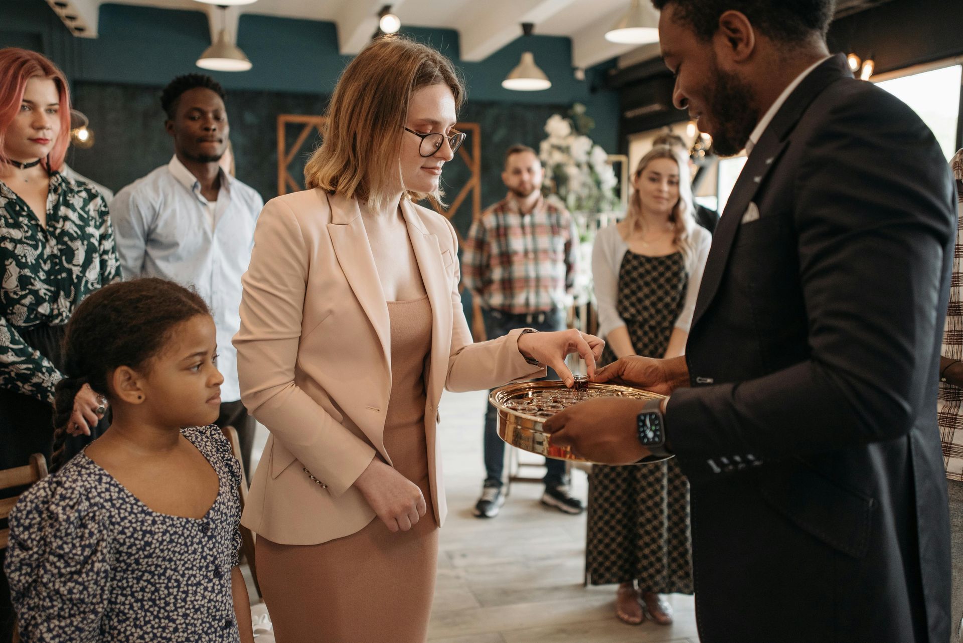 People in a store, a woman gives something to a man holding a bowl; a child watches.