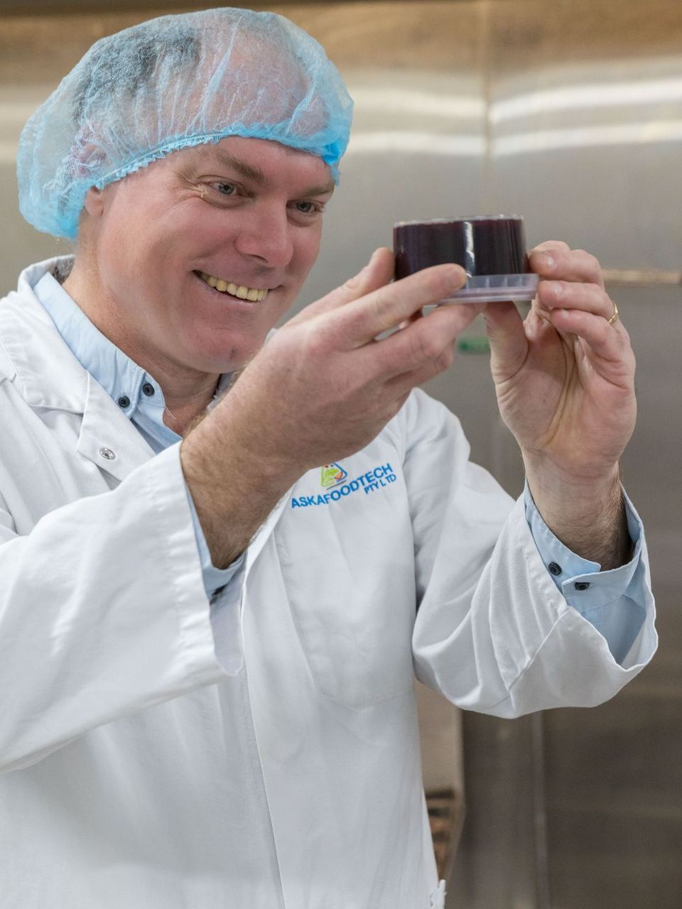 Stewart Eddie in a lab coat is holding a container in his hands.