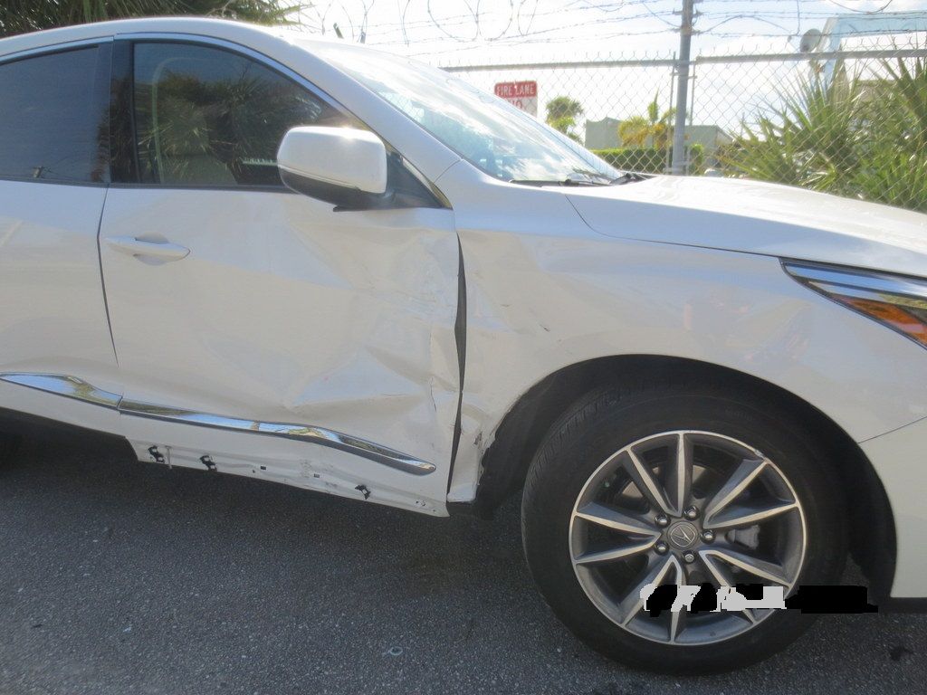 A white car with a damaged side is parked on the side of the road | B & R Auto Body Works