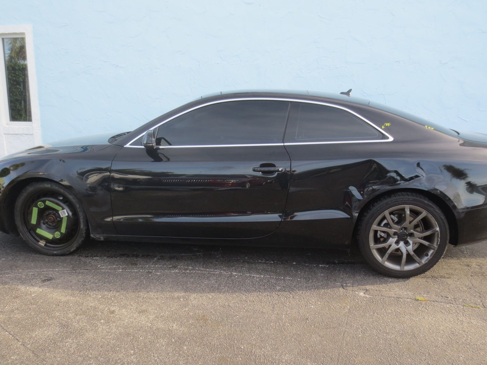 A black car is parked in front of a blue building | B & R Auto Body Works