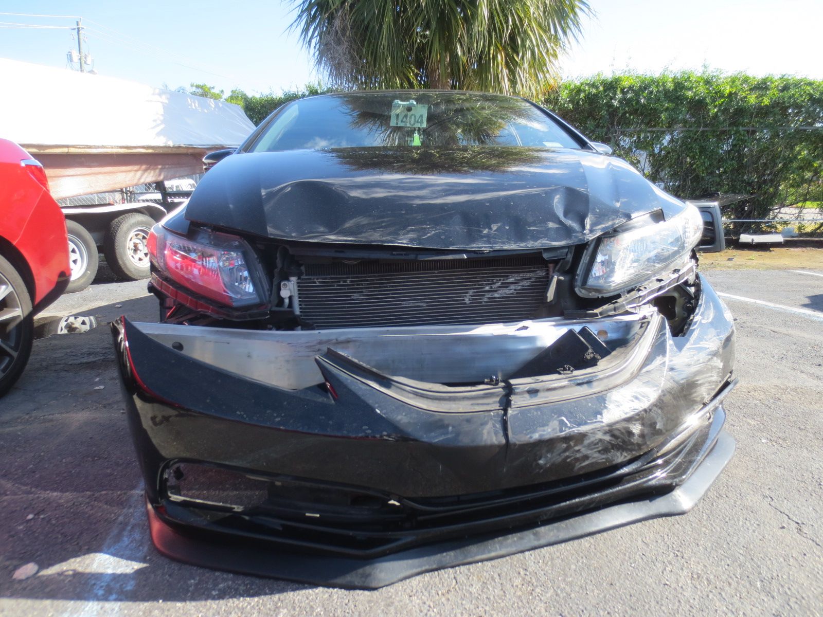 A black car with a damaged front end is parked in a parking lot | B & R Auto Body Works