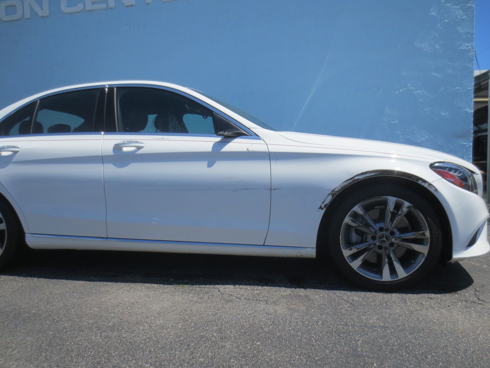 A white car is parked in front of a blue wall | B & R Auto Body Works
