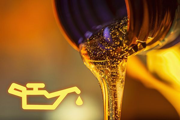 Golden motor oil pouring from a container, with a glowing oil warning icon beside it. | Jeff's Automotive, Inc