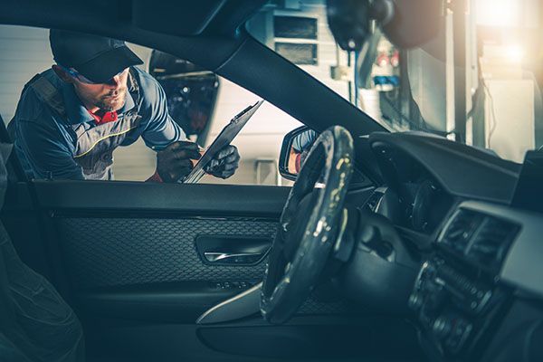 Mechanic inspecting a car interior, using a flashlight in a garage. | Jeff's Automotive, Inc
