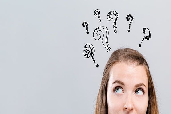 Woman looking up at question marks and a lightbulb doodle, appearing confused and thoughtful | Jeff's Automotive, Inc