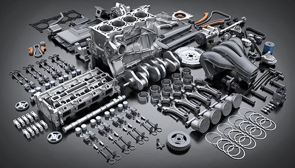 Assorted gray metal automotive engine parts and tools arranged on a dark surface | Jeff's Automotive, Inc
