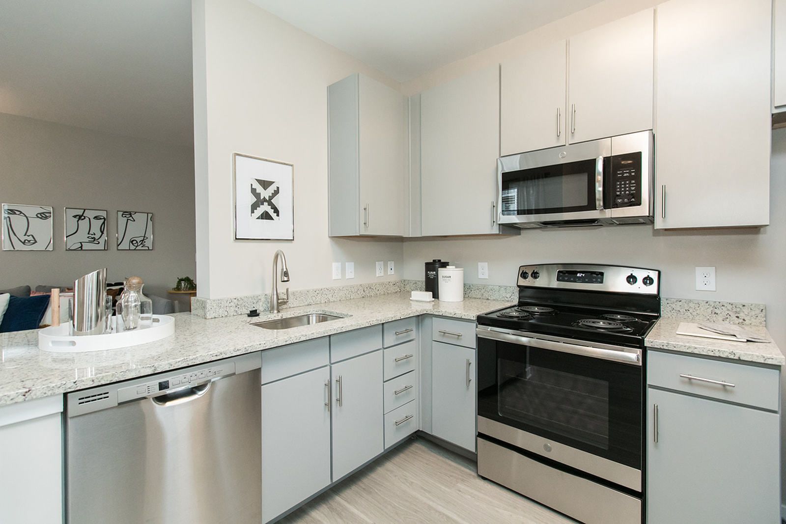 Modern white kitchen with stainless steel appliances, granite counters, and light tile flooring at The Villas at Mill Run Apartments in Owings Mills, MD.