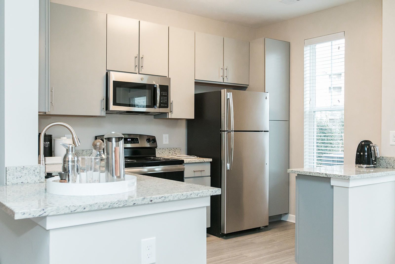 Bright modern kitchen with stainless steel appliances, white cabinets, and a small island by a window at The Villas at Mill Run Apartments in Owings Mills, MD