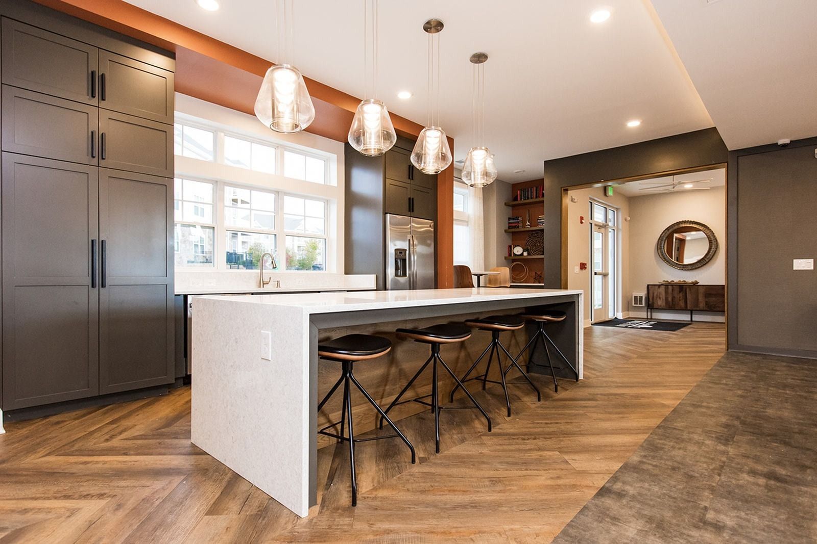 Modern kitchen with large island, pendant lights, dark cabinets, and stools by a bright window at The Villas at Mill Run Apartments in Owings Mills, MD