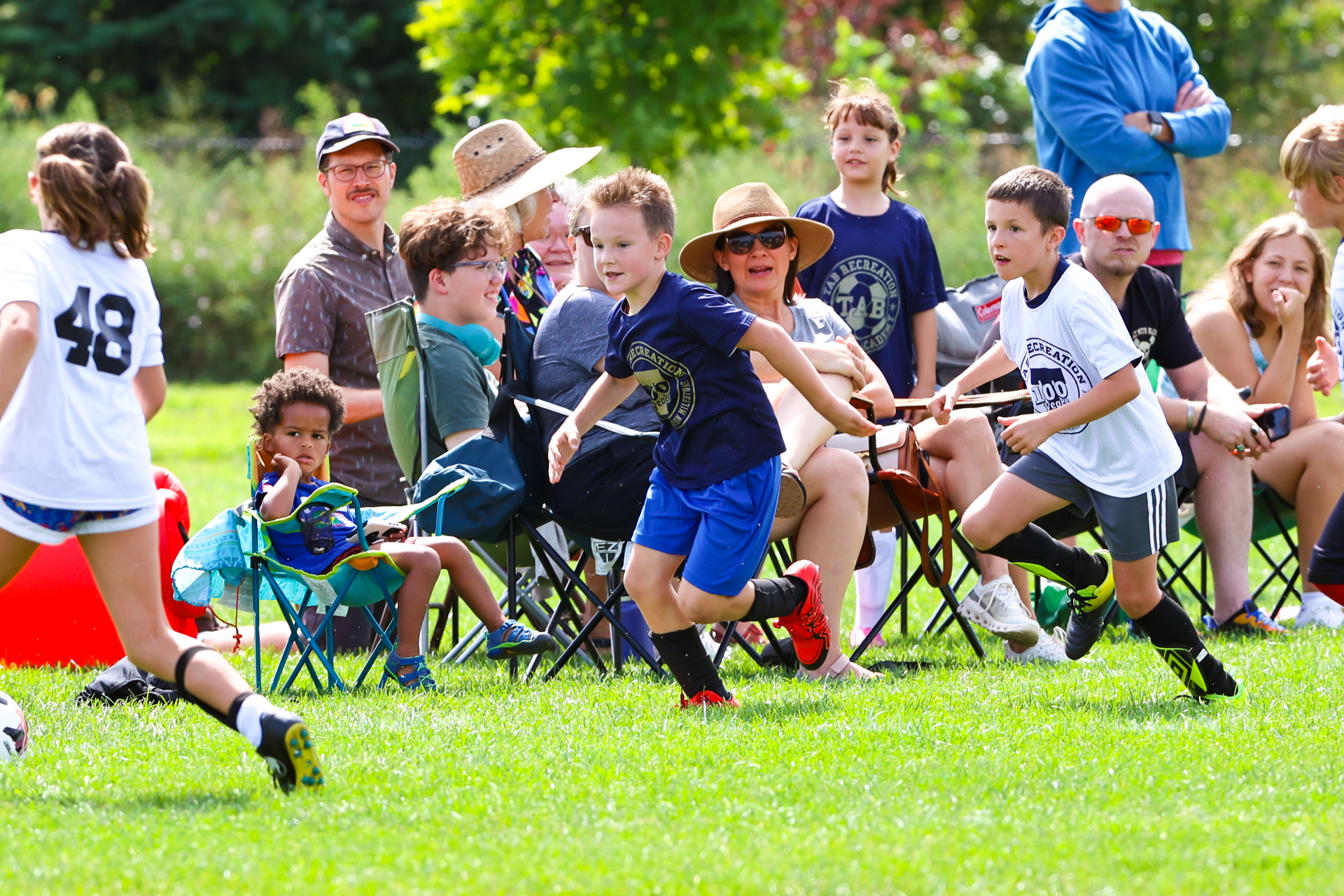 Children playing tug-of-war on a grassy field during an outdoor event