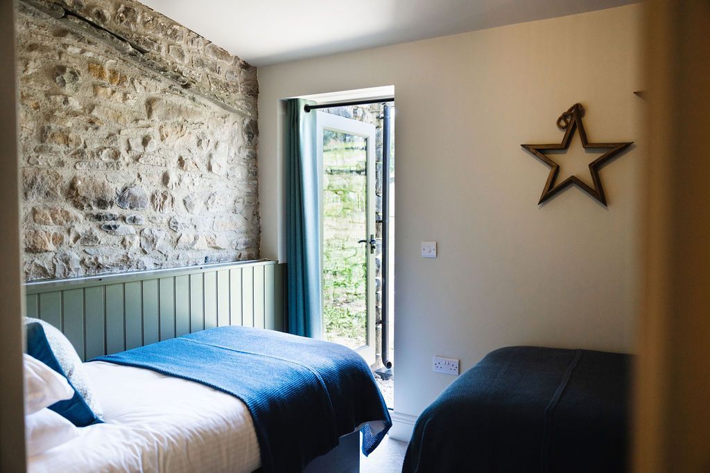 Small bedroom with blue bedding, stone accent wall, open door, and star wall decor.