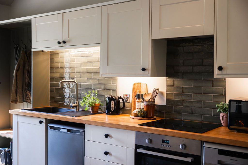 Bright white kitchen with wooden countertops, tiled backsplash, and small appliances on the counter