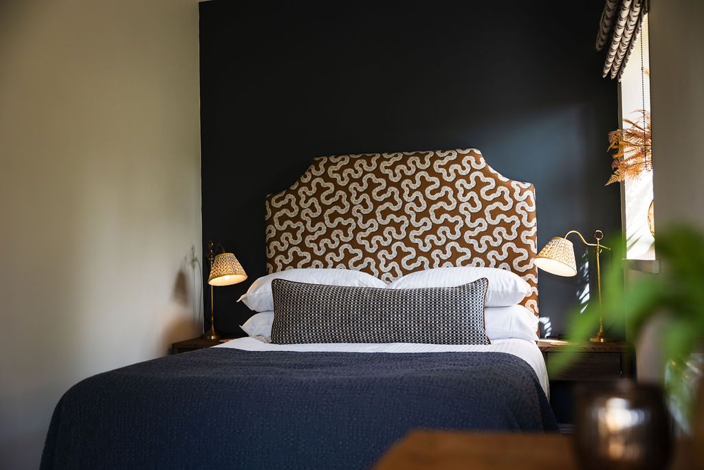 Modern bedroom with patterned headboard, dark wall, and navy bedding