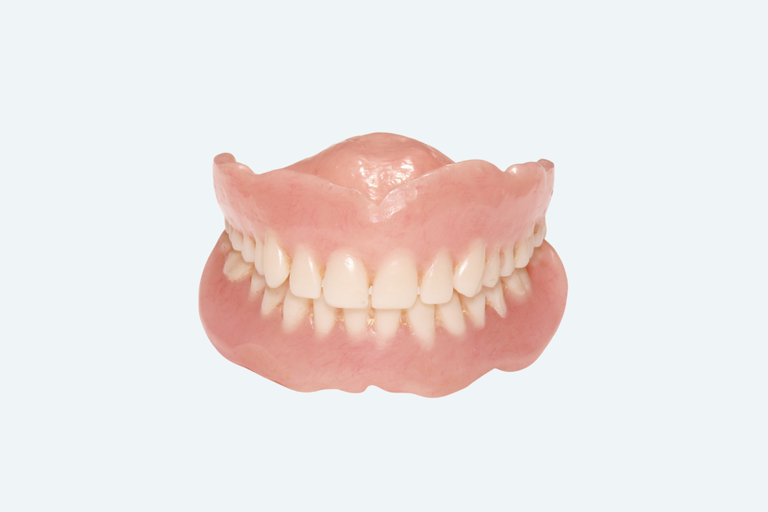 Dentures, upper and lower sets, with pink gum-colored base and rows of white teeth, against a white background.