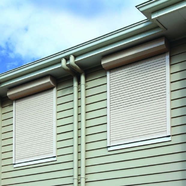 House exterior with light green siding and two closed white shutters under the roofline