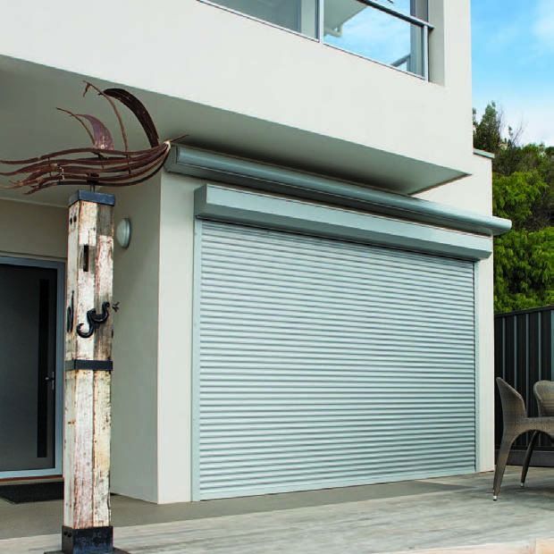 Modern house exterior with a closed light-blue garage door and a small patio area