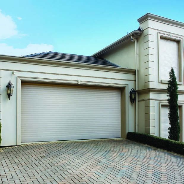 Modern house exterior with a closed white garage door and tiled driveway