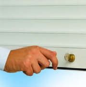 Closed metal garage door behind a green hedge and paved walkway