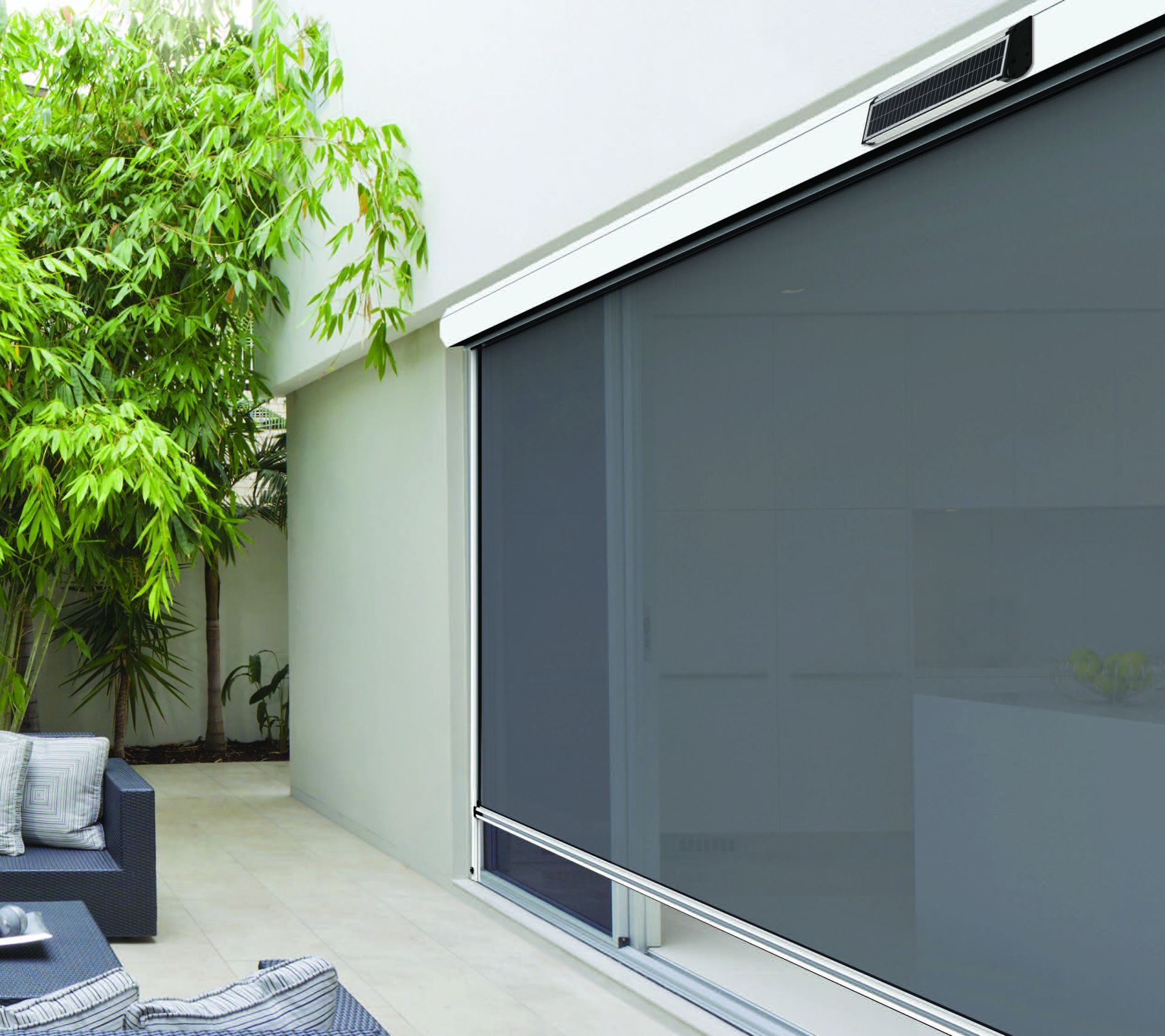 Patio with a dark gray retractable screen beside a potted tree and outdoor seating area