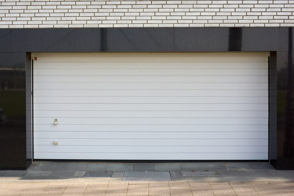 White roll-up garage door set in a dark frame beneath a brick facade