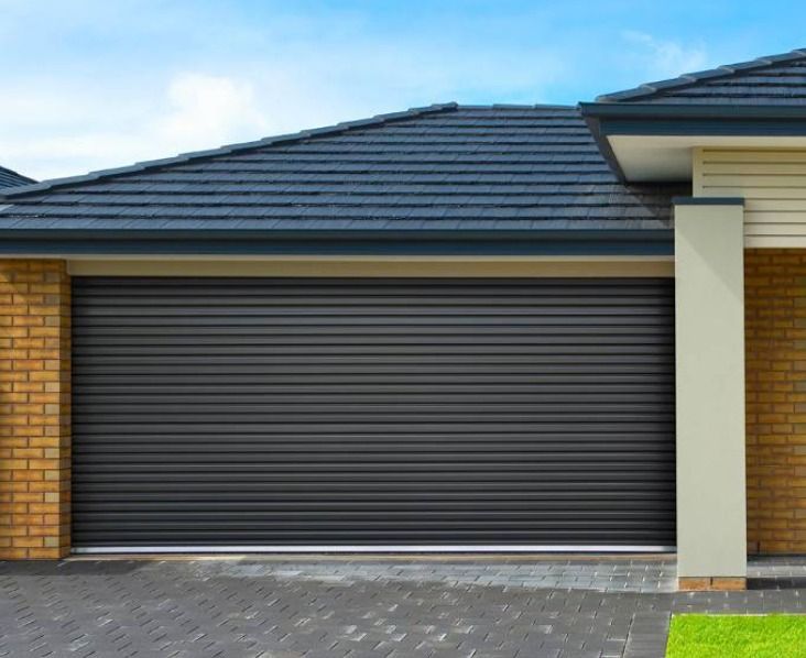 Modern house facade with a closed gray roller garage door and brick walls