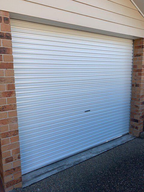 Closed white roller garage door between brick walls