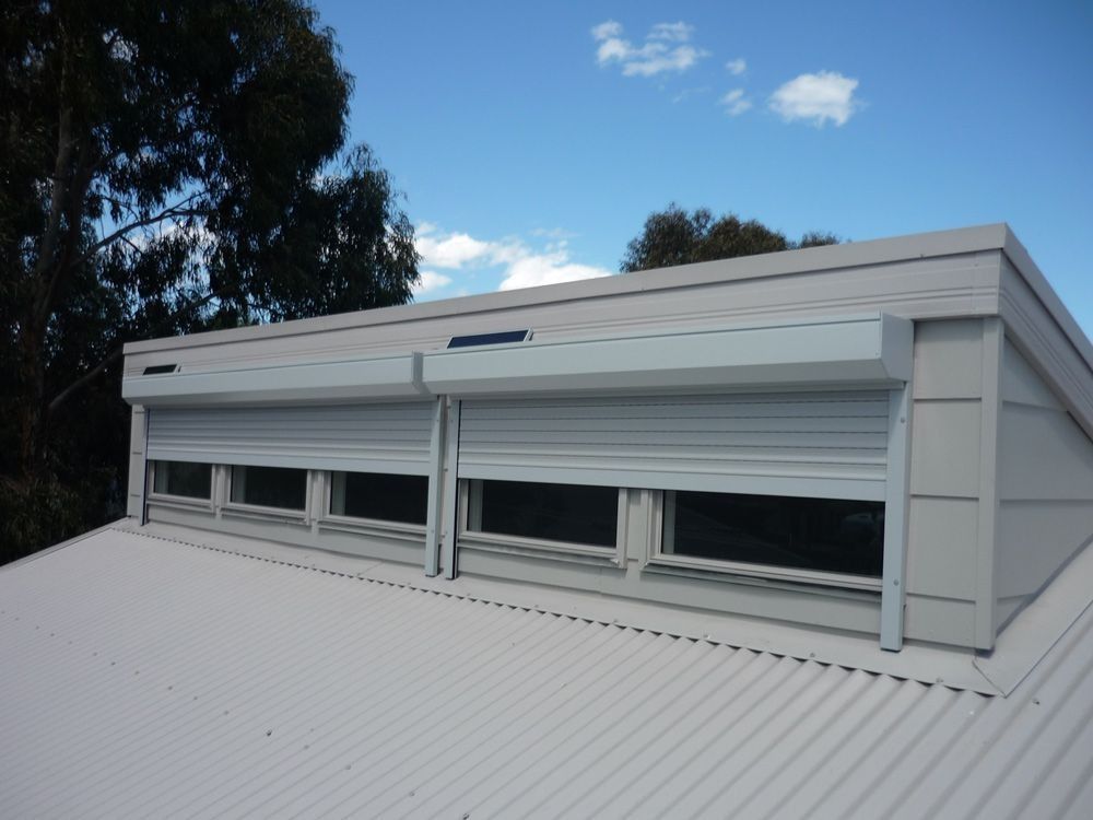 White rooftop window with horizontal blinds on a modern building under a blue sky