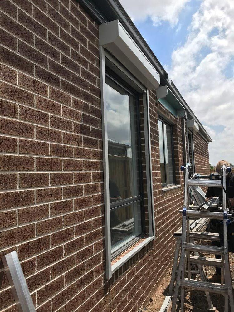 Brick house exterior with windows and a ladder during window work