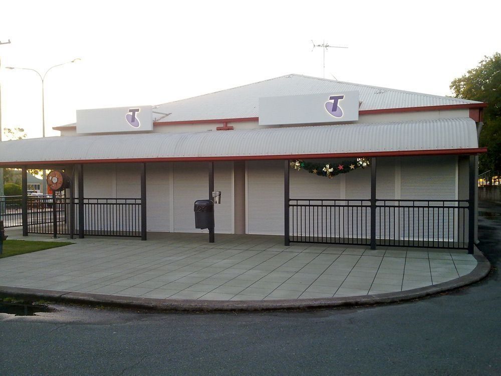 Closed concession stand with white roof and black gates at an empty entrance plaza.