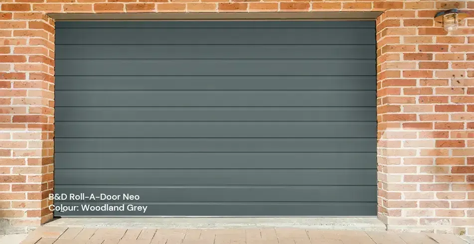 Closed gray garage door set in a red brick wall with a concrete floor.