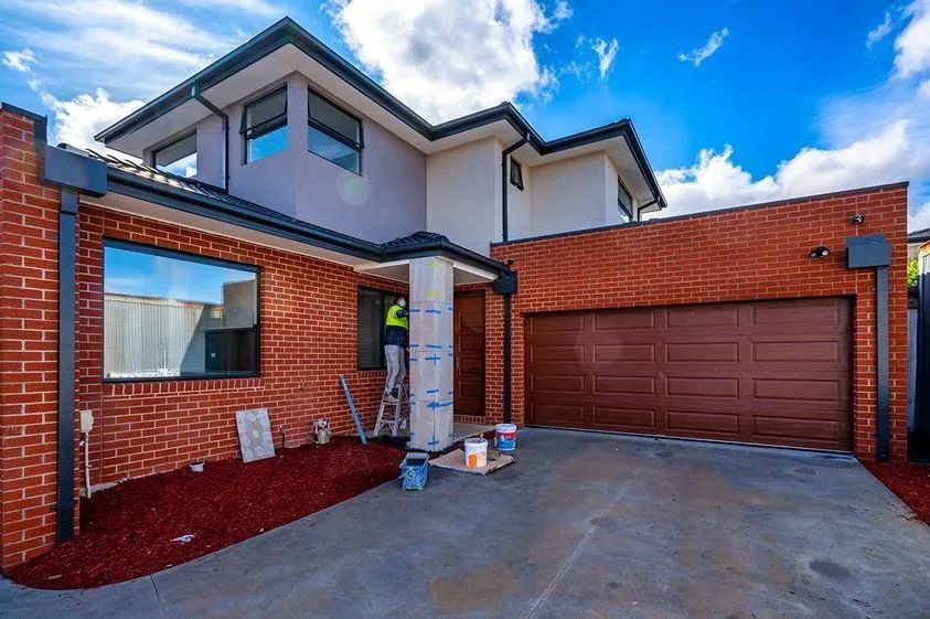 Modern brick house exterior with driveway and double garage under a blue sky
