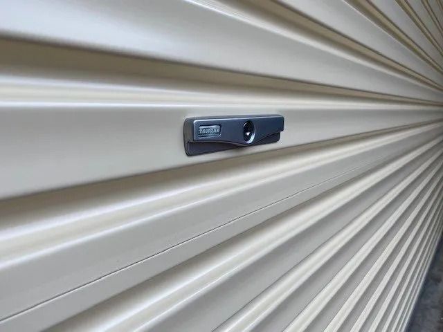 Close-up of a metallic latch on a beige corrugated garage door