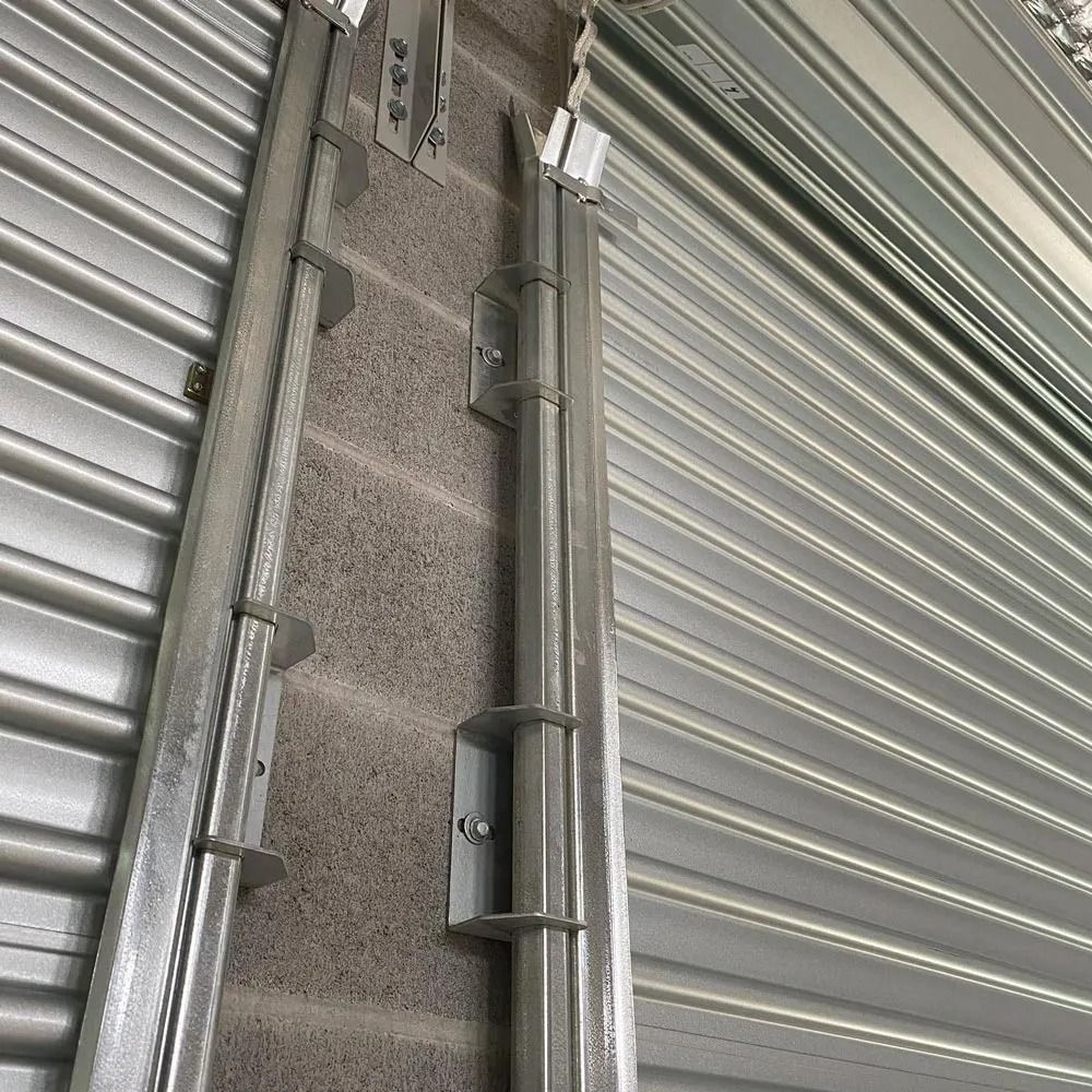 Close-up of a gray metal roller shutter with a small wall-mounted sensor or light fixture.