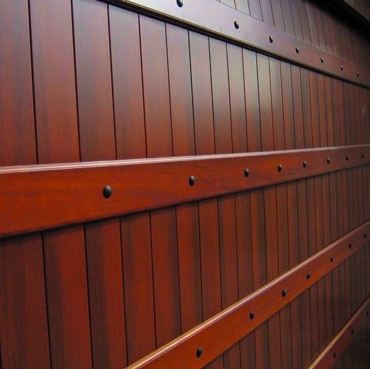 Close-up of a reddish-brown wooden gate with horizontal metal-reinforced beams and rivets