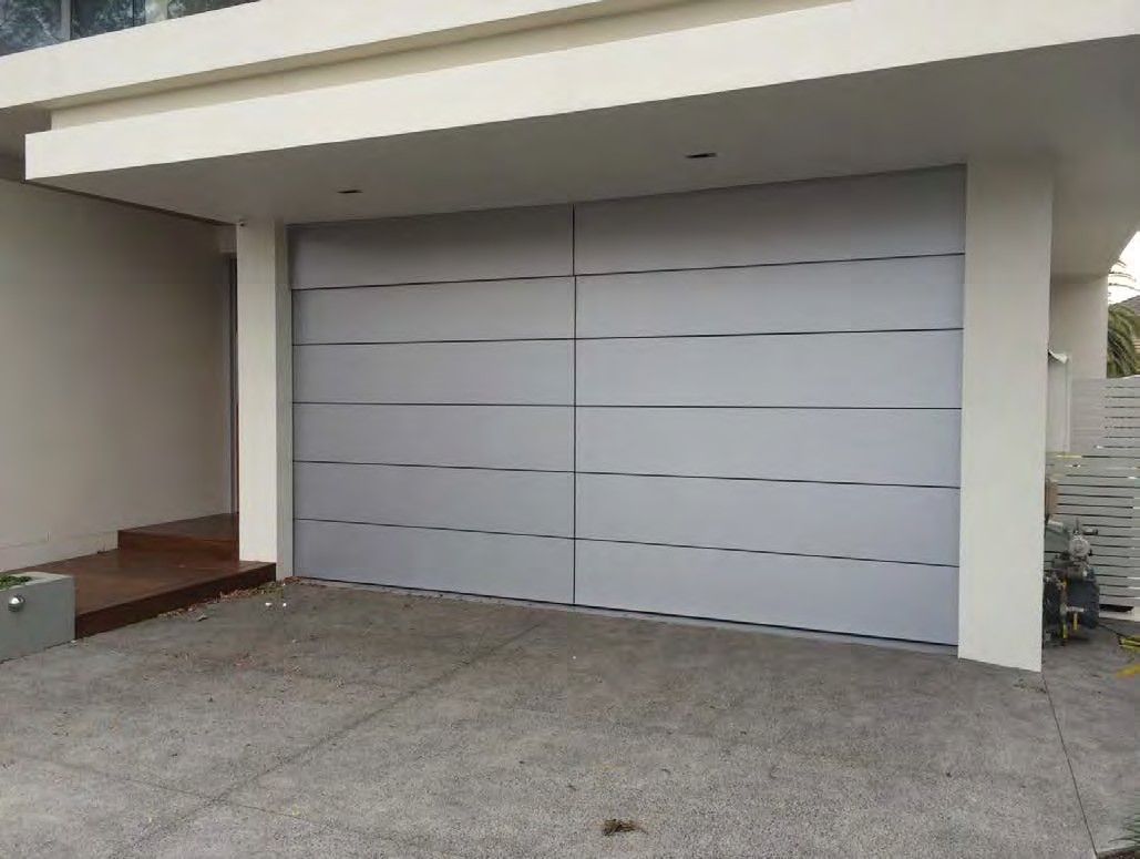 Modern house exterior with a large gray garage door and concrete driveway