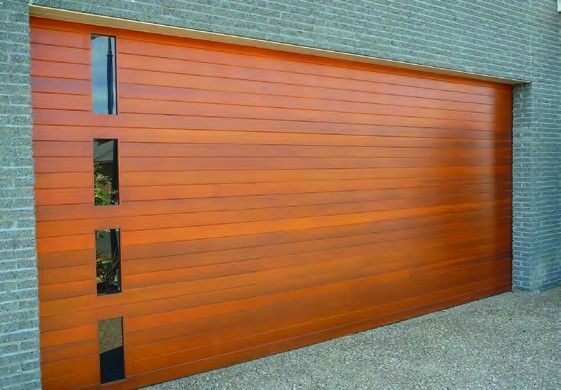 Orange wooden garage door with narrow vertical windows in a brick wall
