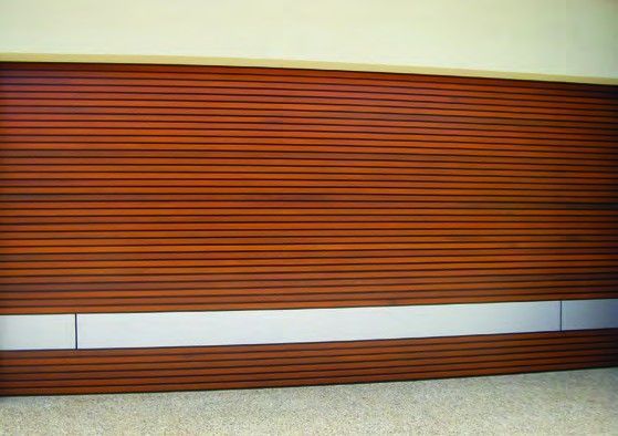 Horizontal wooden blinds with a brown slat pattern above a white baseboard and carpeted floor