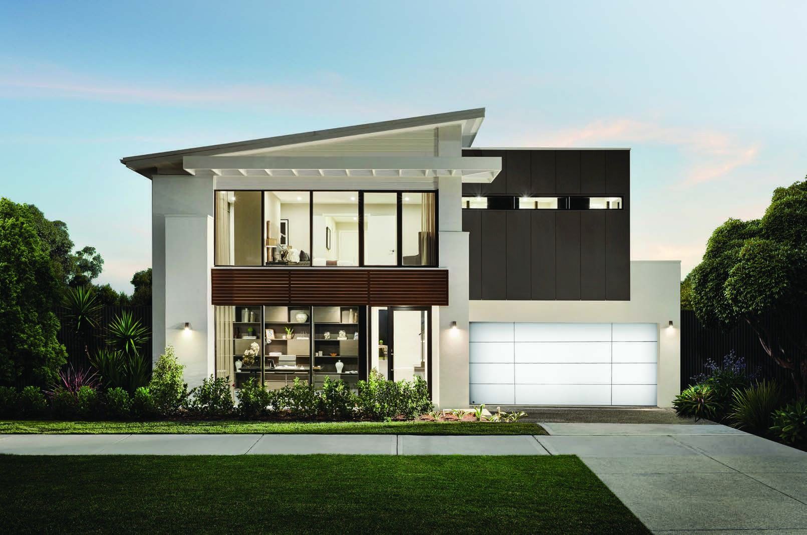 Modern two-story house with large windows, a white garage, and a landscaped front yard at dusk