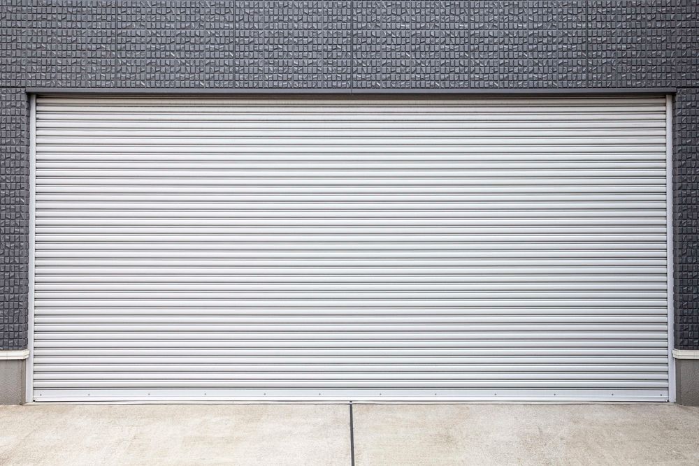 Closed white roll-up garage door on a gray building wall