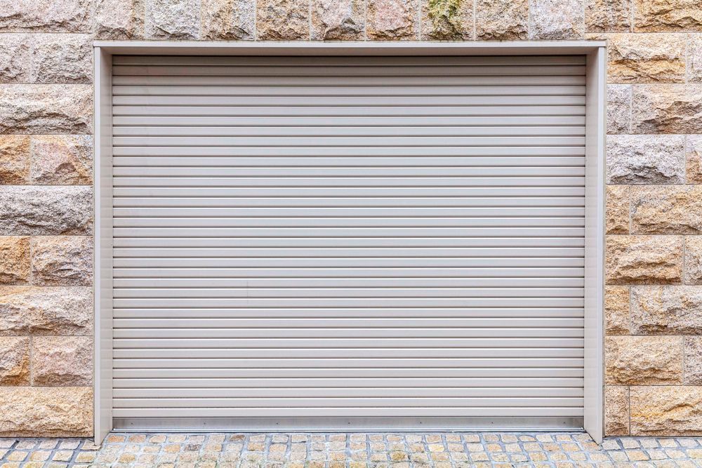 Closed beige metal garage door set in a stone wall