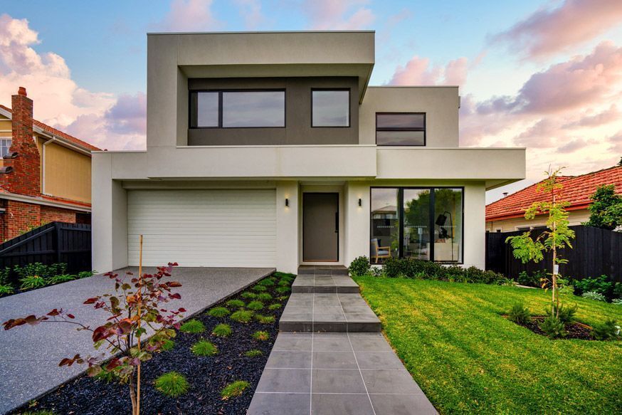 Modern two-story house with a garage, front walkway, and landscaped lawn at sunset