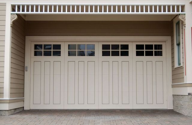 Beige double garage door with small upper windows on a house exterior